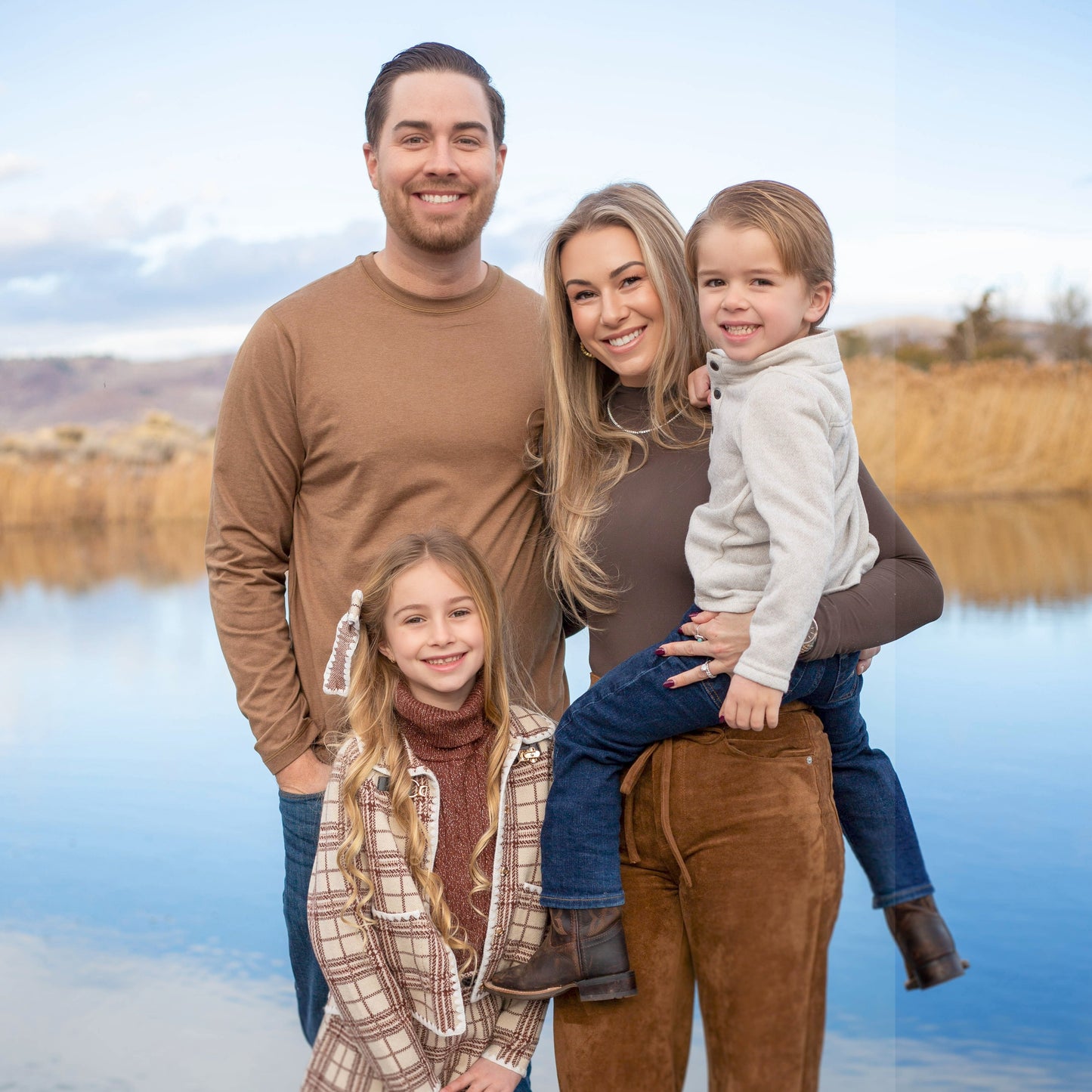 Family of four standing on a dock by a lake